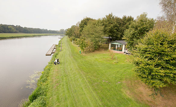 Angler fishing in a canal beside a chalet at Arendshorst Resort in Holland/