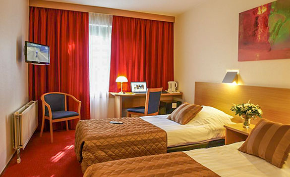 twin bedded hotel room with red carpet and curtains and brown bedding/