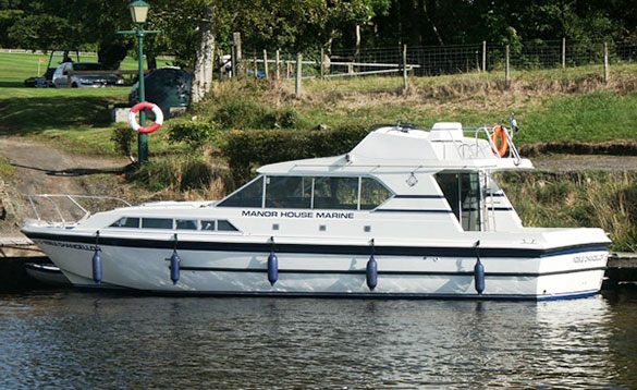 large white cruiser moored at a jetty with a golf course in the background/