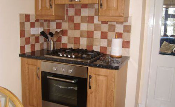 oven with gas hob and pine kitchen units and brown checkerboard tiles/