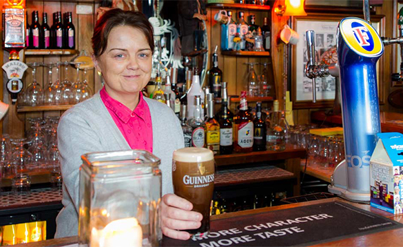 Lady serving a pint of Guinness in O'Callaghan's Bar, Coachford/