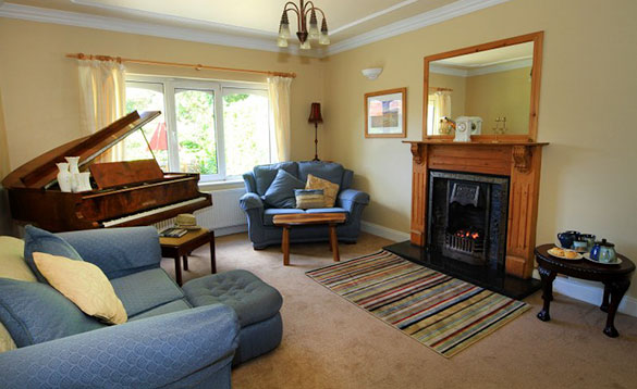 living room with grand piano in the corner and blue sofa and chairs/