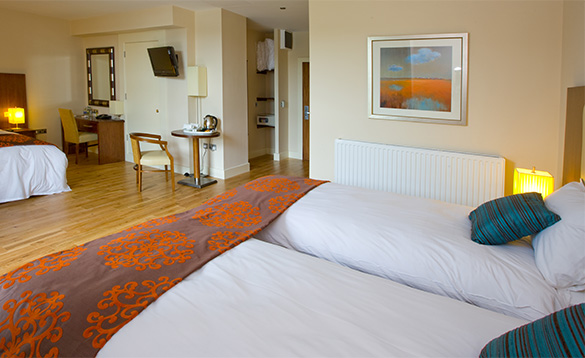 Hotel bedroom with three single beds with white bed linen and blue cushions/