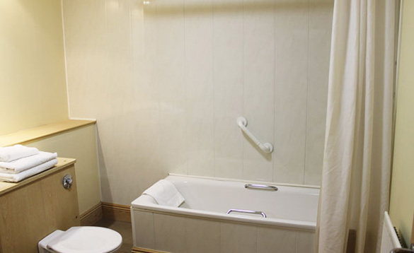 bathroom with white bathroom suite and tiled walls and cream shower curtain/