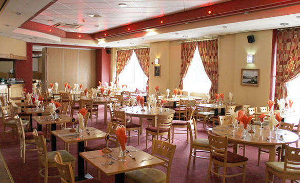 hotel restaurant with pink carpet and table set for dinner/
