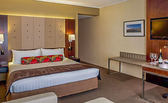 hotel room with double bed, cream walls and brown carpet/