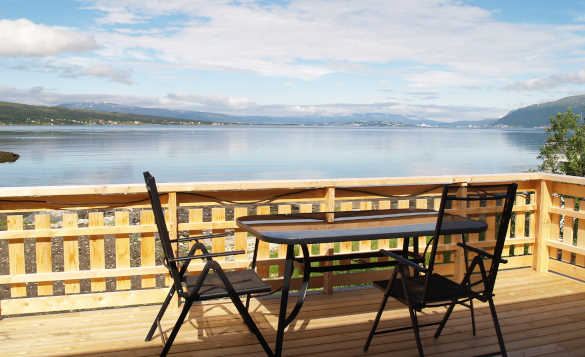 Table and chairs on a veranda with views out over a fjord in North Norway/