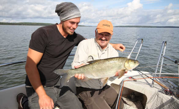 Two anglers on a boat, one holding a asp fish caught in Sweden/