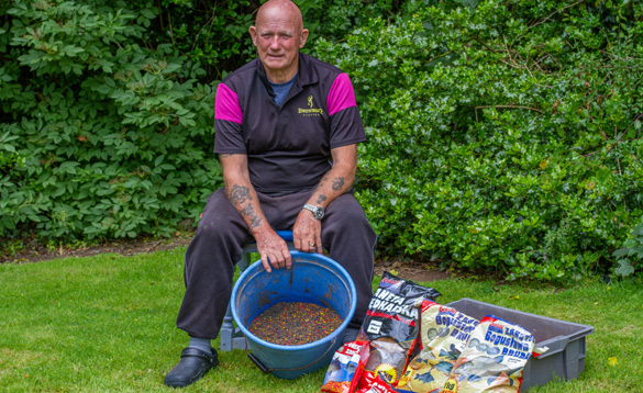 Angler sat on a stool with bags of groundbait/