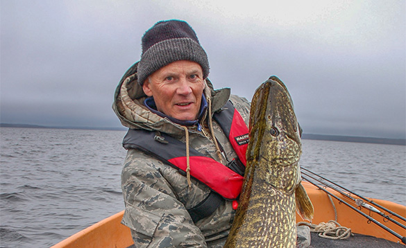 Angler holding a pike sitting on a boat in Sweden/