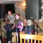 Three piece band singing in a pub