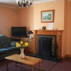 Living room with open fire and pine fireplace and blue sofa beside pine coffee table with daffodils in a vase