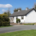 Gravel driveway leading to a white bungalow with grey slate roof