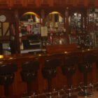 Fully stocked bar in a pub with a row of eight bar stools