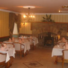 Five tables with white tablecloths set for evening meal in hotel dining room