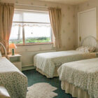 Bedroom with three single beds with green patterned duvets