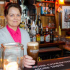Bar maid behind a bar holding a pint of Guinness