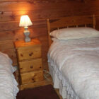 Two single beds in pine clad bedroom with white quilts