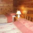 Double and a single bed in a pine clad room with pink patterned bed sheets