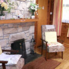 Three arm chairs beside a large stone fireplace