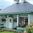 White bungalow with green painted windowsills and grey slate roof