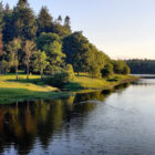 View of a cottage in Ireland set amongst trees and a river flowing past