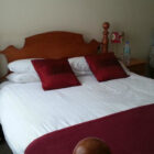 Double bed with white quilt and red throw and cushions