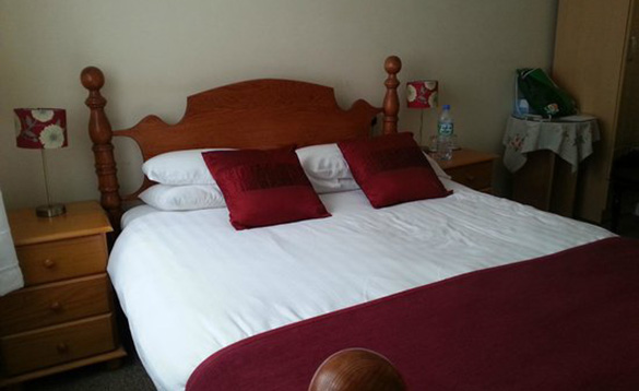 Double bed with white quilt and red throw and cushions
