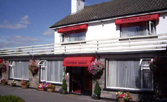 Ireland-fishing-holidays-co-cork-fountain-house-bb(2) White two storey building with hanging baskets and pots full with multicoloured flowers