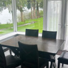 dark wood table with six leather dining chairs next to window with views of a river