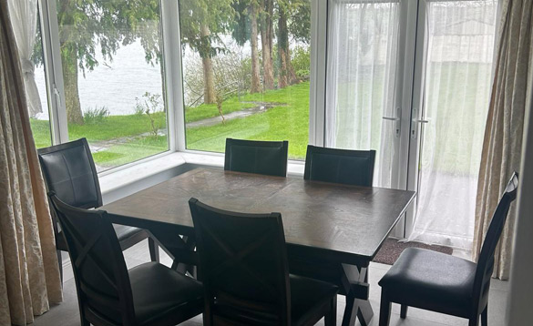 dark wood table with six leather dining chairs next to window with views of a river