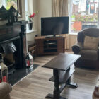Lounge in self-catering property with feature open fireplace and fawn three piece suite around a dark wood coffee table