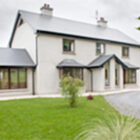 Two storey white building with front proch and sun room attached to the side