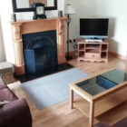 Living room with two burgandy leather sofas, glass coffe table and open fireplace and television on a wooden stand