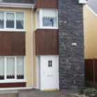 Two storey semi-detached house with cream walls and white door with stone corner