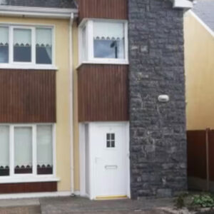 Two storey semi-detached house with cream walls and white door with stone corner
