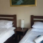 Green and white towels rolled and placed on two single beds with white bed linen