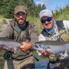 Two anglers each holding a coho salmon