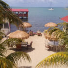 Table, chairs and sun lounges on a beach with palm leave parosols and palm trees