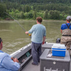 Three anglers fishing from a boat on a river