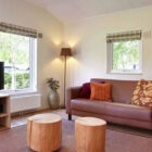 Living room with wooden floor and pink leather sofa and two lighter pink chairs around a carpet