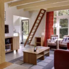 Living room with red leather sofa, small coffee table and ladder leading up to the upper floor