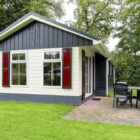 Wooden chalet painted cream and black with brick paved deck area with table and chairs