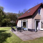Brick built dorma bungalow with red tiled roof and french doors leading to paved area with table and chairs on it