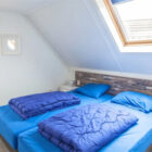 Bedroom with sloping roof and two single beds with dark blue bed linen