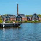 Family on a boat with outboard motor crusing past some dorma bungalows