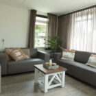 Lounge with light oak wooden floor and two fawn leather settees with brown and cream cushions