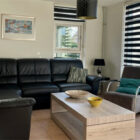 Lounge with black leather corner settee and black and white striped blinds at two windows