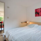 Bedroom with double bed with white linen and picture of pink tulips on the wall