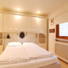 Bedroom with cream cupboards and a double bed with white linen